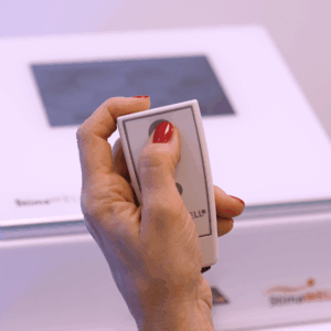 Hand hält eine StimaWELL-Fernbedienung, mit der sich die Behandlungsintensität individuell einstellen lässt.